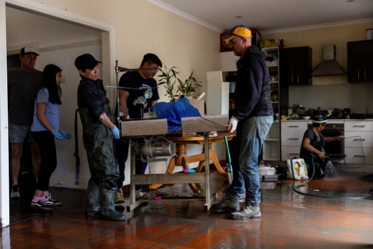 Local residents clean the inside of a home affected by floodwaters near the Maribyrnong River in Melbourne, Australia