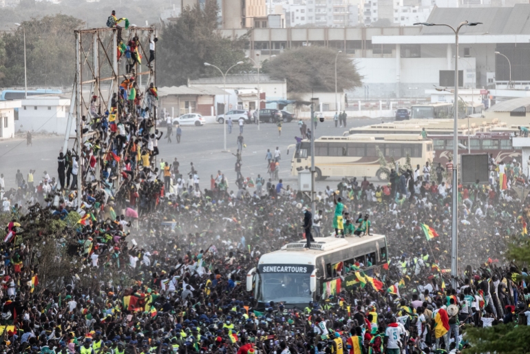 Supporters cheer as a member of the Senegalese Football team raises the trophy in Dakar