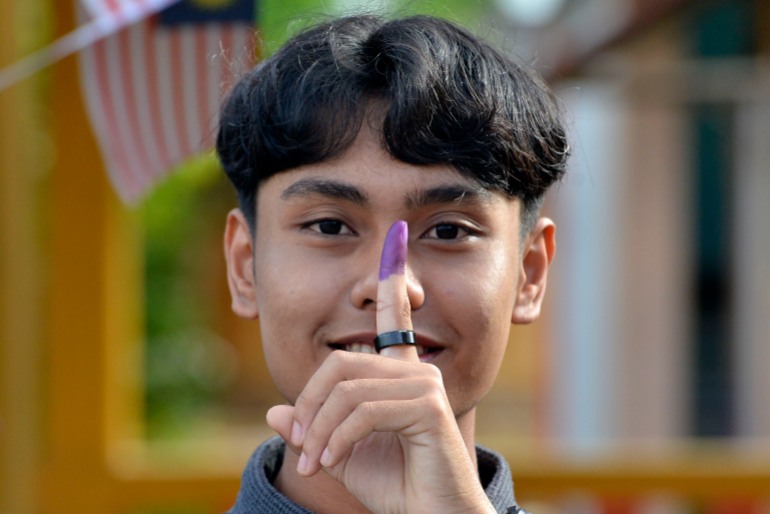 A young male voter shows his inked finger after casting his ballot in Malaysia