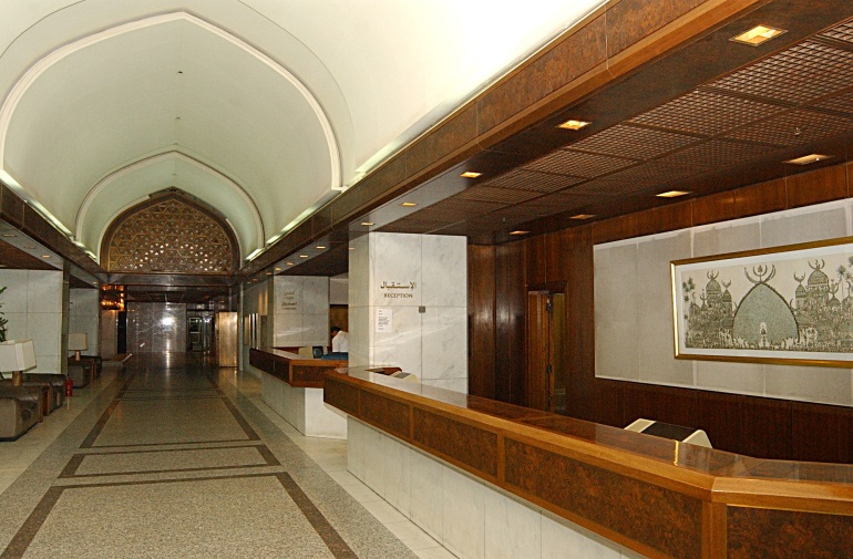 A photo of a hotel lobby with a long hallway and a reception/concierge desk.