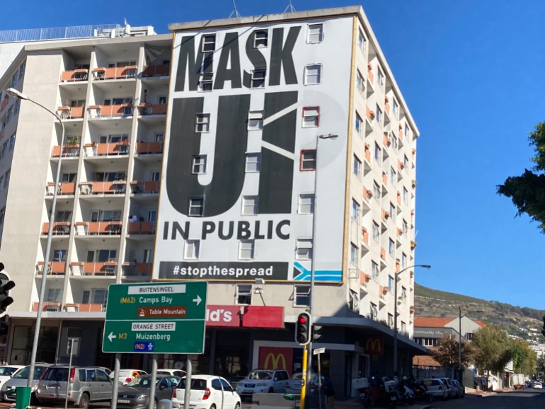 A banner on a building in Cape Town reads: Mask up in public
