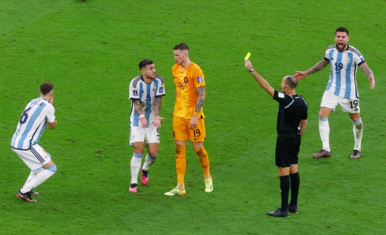 Argentina's German Pezzella is shown a yellow card by referee Antonio Mateu Lahoz as Nicolas Otamendi and Leandro Paredes react on December 9, 2022, during the match against the Netherlands.
