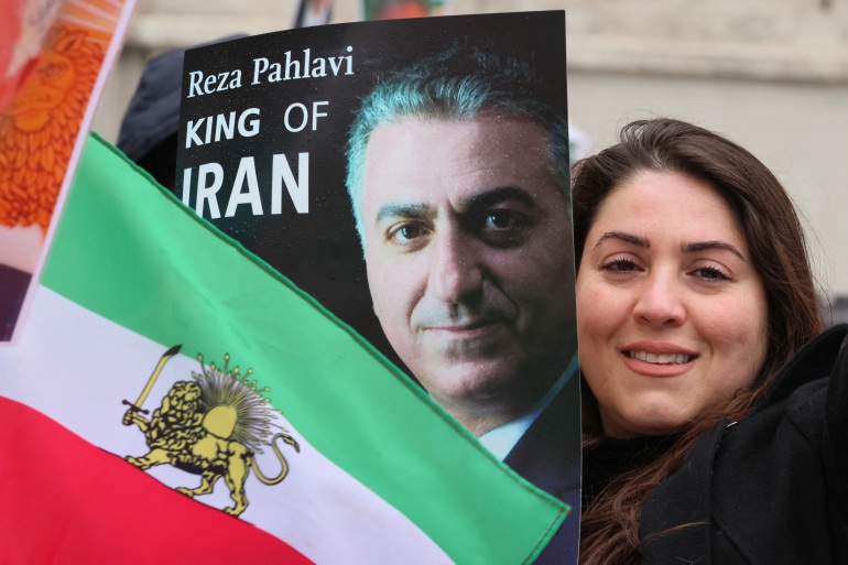 A woman poses with an Iranian flag and a portrait of Reza Pahlavi, which reads "king of Iran"