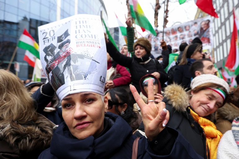 A protester wears a headdress made of a sheet of paper denouncing Iran's IRGC as "terrorists"