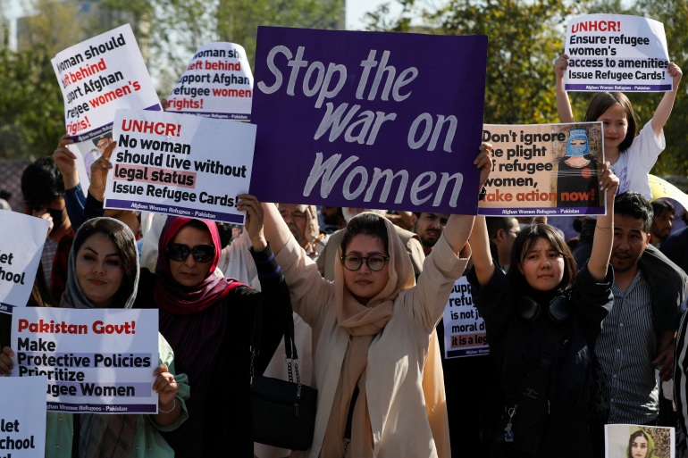 Afghan women refugees carry signs, as they participate in Women's March in Islamabad.
