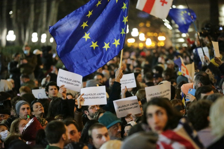 Protesters in Tbilisi brandish placards and a European Union flag