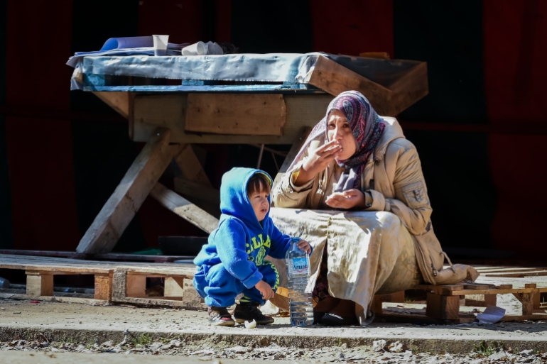 A woman and child eat in front of a deserted food stand in a tent camp for refugees in Brussels on Thursday, Oct. 1, 2015. Civil organizations, city services and NGO's dismantled the tent camp in which several 100 refugees have lived for some weeks as they apply for asylum in Belgium, but volunteers have decided it was no longer suitable for refugees to live outside and have found local families to host the migrant families.(AP Photo/Geert Vanden Wijngaert)