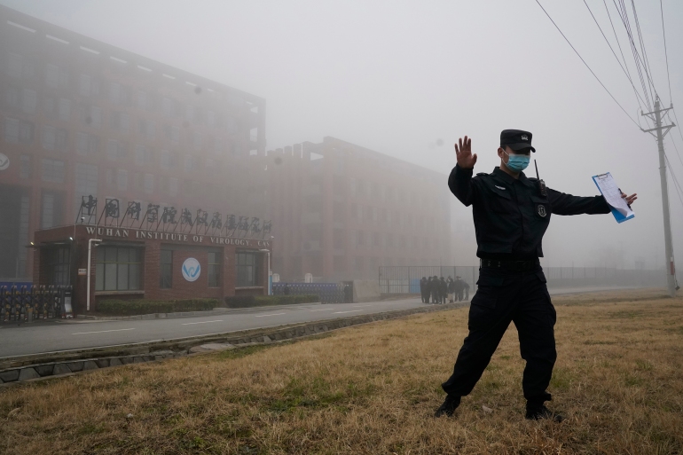 A security official moves journalists away from the Wuhan Institute of Virology after a World Health Organization team arrived for a field visit in Wuhan in China's Hubei province on Wednesday, Feb. 3, 2021. The WHO team is investigating the origins of the coronavirus pandemic has visited two disease control centers in the province. (AP Photo/Ng Han Guan)