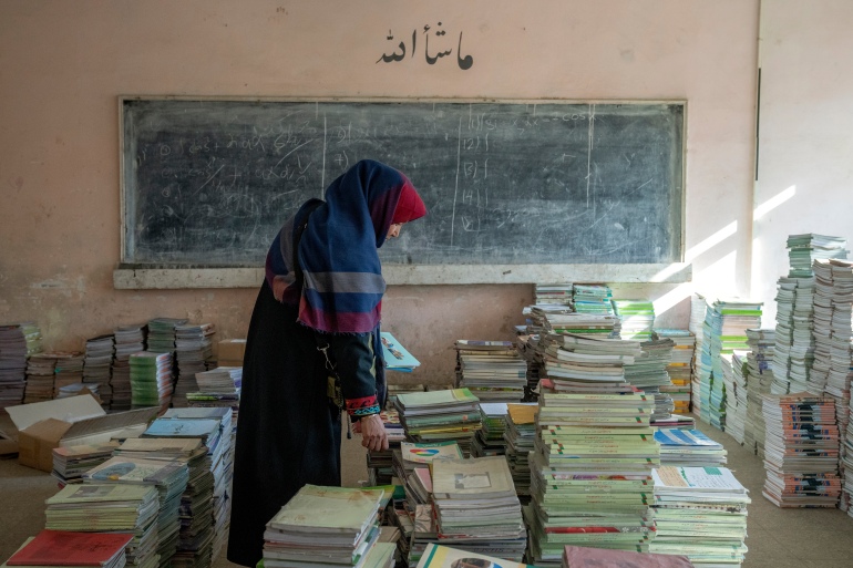 Amanah Nashenas, a 45-year-old Afghan teacher, collects books in a school in Kabul, Afghanistan, on December 22, 2022 [Ebrahim Noroozi/AP Photo]