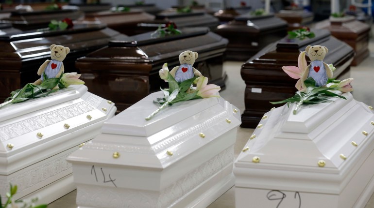  In this Saturday, Oct. 5, 2013 file photo, teddy bears and flowers placed on the coffins of deceased migrants are seen inside a hangar at Lampedusa's airport, Italy, Saturday, Oct. 5, 2013.